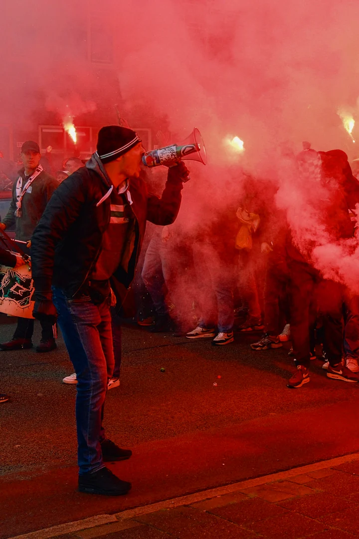 Supporter spreekt met een megafoon voor een menigte met fakkels