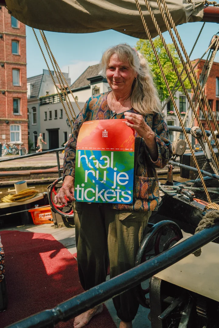 Vrouw toont een Noorderzon-poster vanaf een historische boot in Groningen