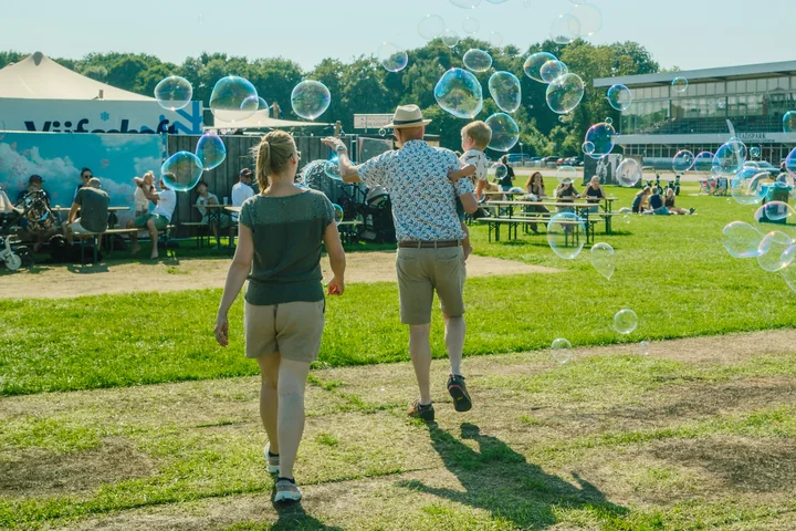 Gezin wandelt door een veld vol zeepbellen in het Stadspark